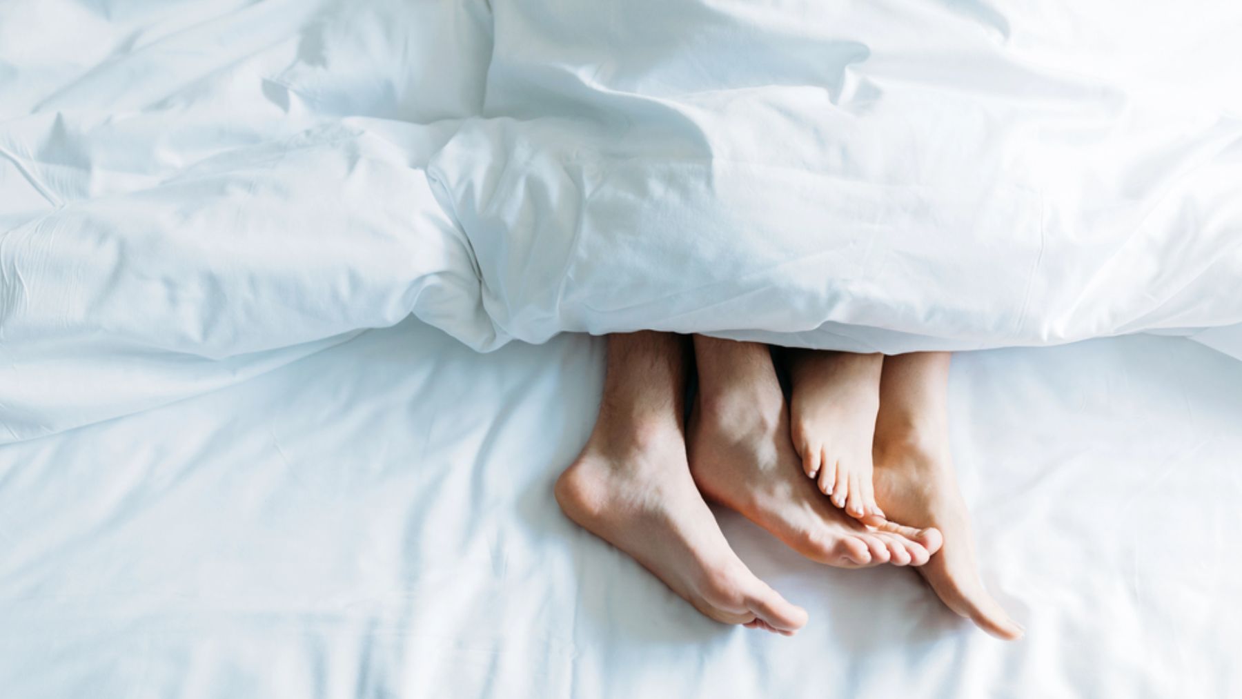 Los pies de una pareja en la cama.