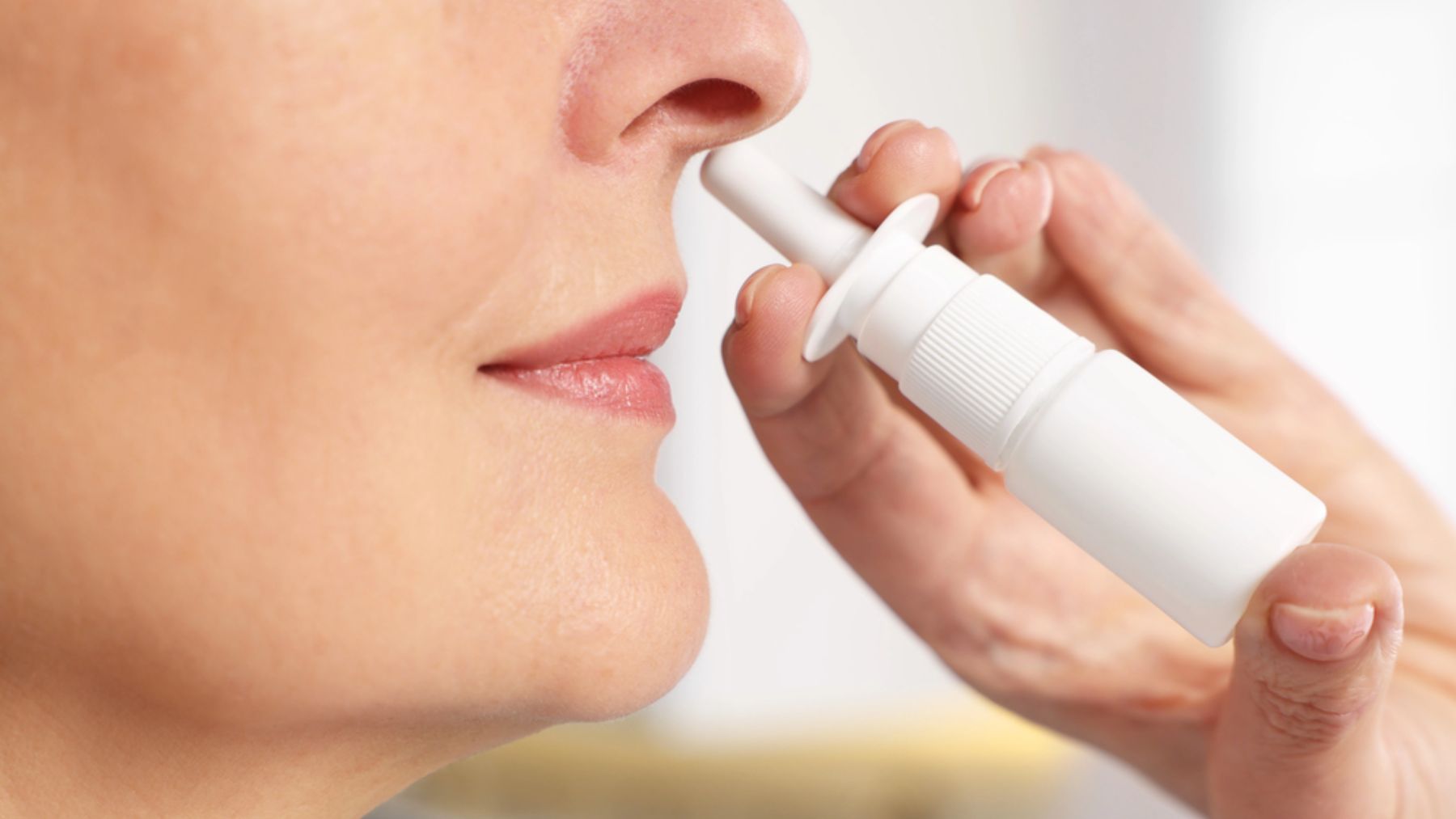 Una mujer se aplica un spray nasal.