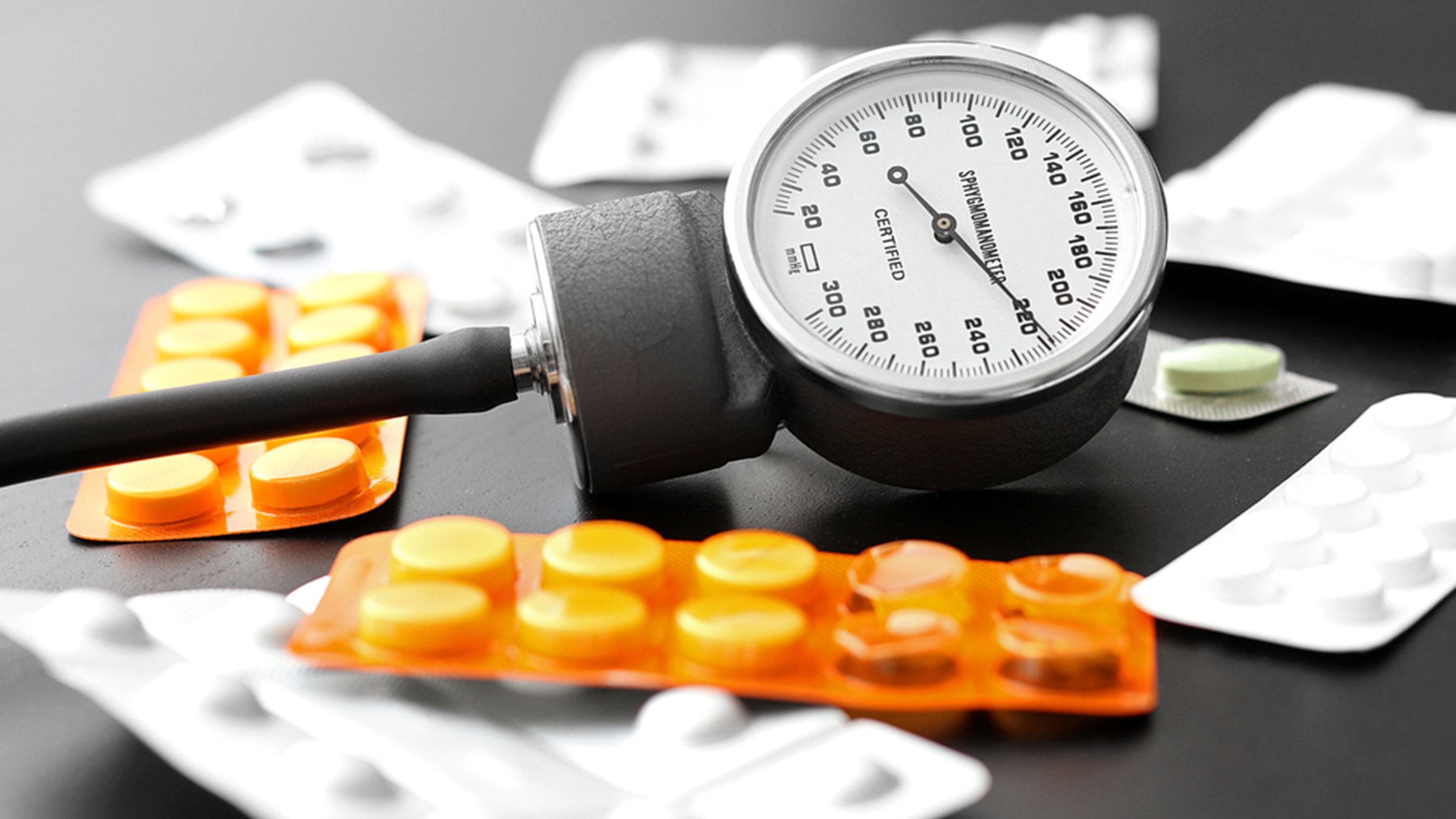 Un tensiómetro rodeado de medicamentos.